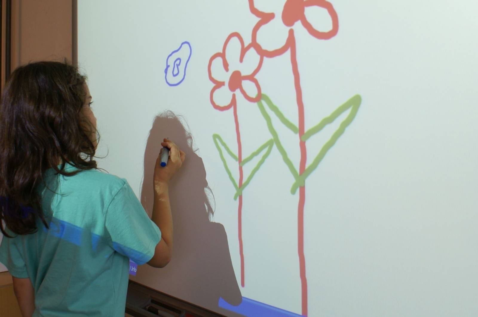 Ein Kind vor Whiteboard malt eine Blume